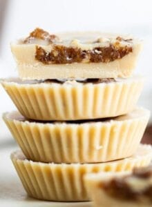 A stack of 4 tahini cups with dates inside, one cut in half to show inside.