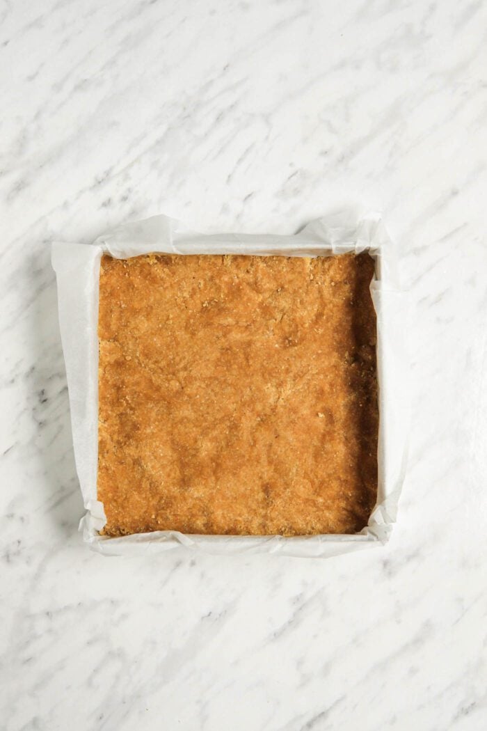 Dough pressed firmly into a square baking pan.