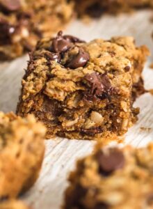 A number of peanut butter banana oatmeal chocolate chip cookie bars on a piece of parchment paper.